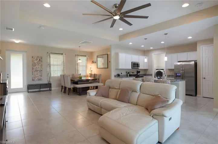 Living room with light tile patterned flooring, ceiling fan, and a tray ceiling