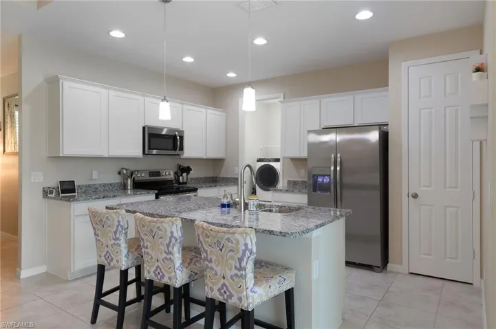 Kitchen with hanging light fixtures, stainless steel appliances, and a center island with sink