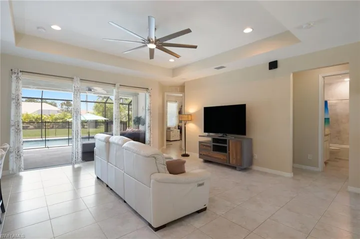 Tiled living room featuring ceiling fan and a tray ceiling