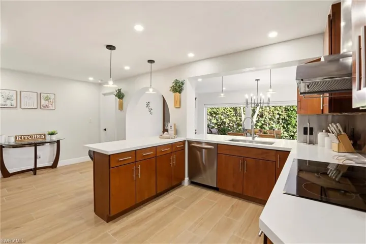 Kitchen featuring a peninsula, decorative light fixtures, brown cabinets, wood tiled floors, and recessed lighting