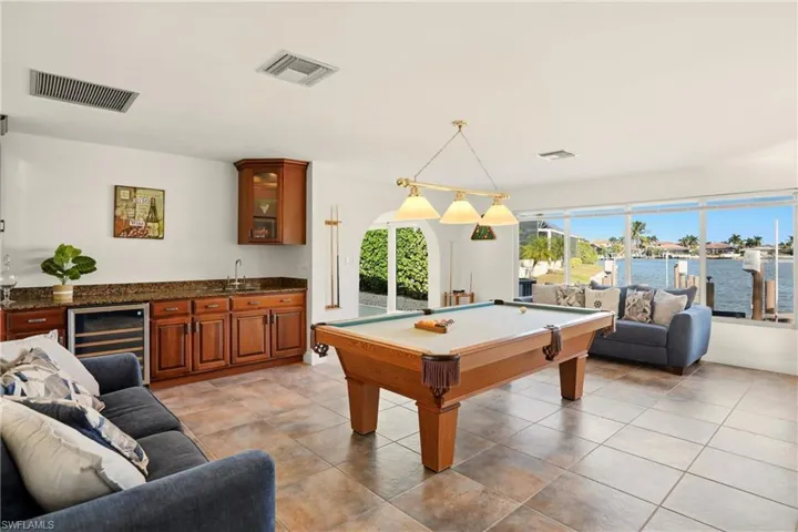 Game room featuring billiards table, wine cooler, a water view, and wet bar