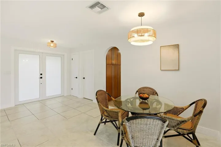 Dining space with french doors, arched walkways, and light tile patterned floors