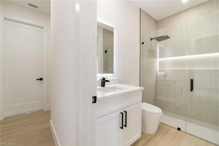 Bathroom featuring vanity, an enclosed shower, hardwood / wood-style flooring, and toilet