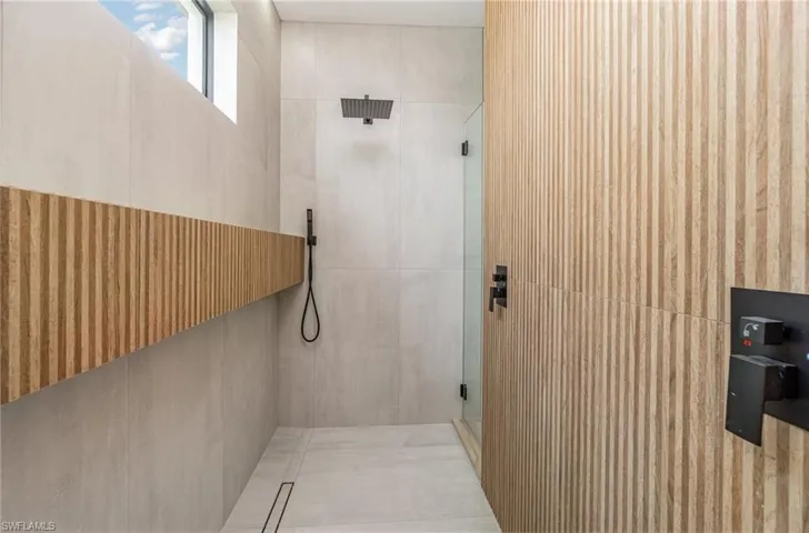 Bathroom featuring a shower with shower door and tile walls