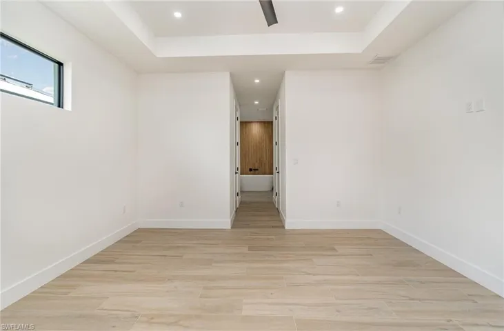 Unfurnished room with light hardwood / wood-style flooring and a tray ceiling