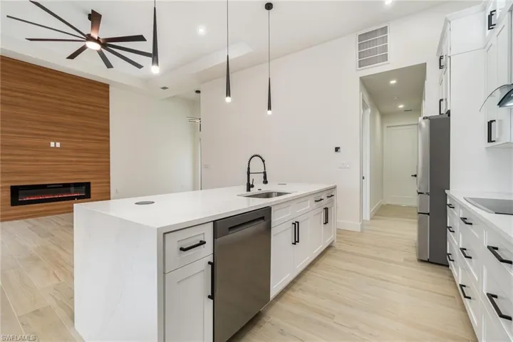 Kitchen with white cabinets, ceiling fan, light hardwood / wood-style floors, appliances with stainless steel finishes, and sink