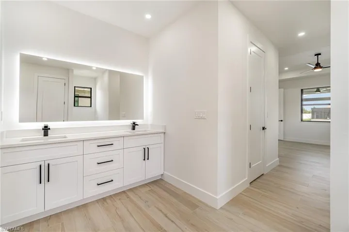 Bathroom with double vanity, ceiling fan, and hardwood / wood-style floors