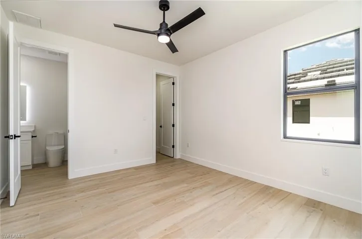Unfurnished bedroom with light hardwood / wood-style floors, ensuite bath, and ceiling fan
