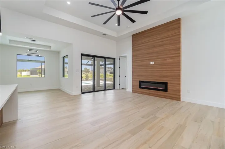 Unfurnished living room with a large fireplace, light hardwood / wood-style flooring, a wealth of natural light, and a tray ceiling