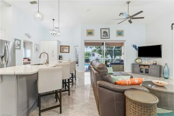 Living area with ceiling fan, a high ceiling, and light marble finish floors