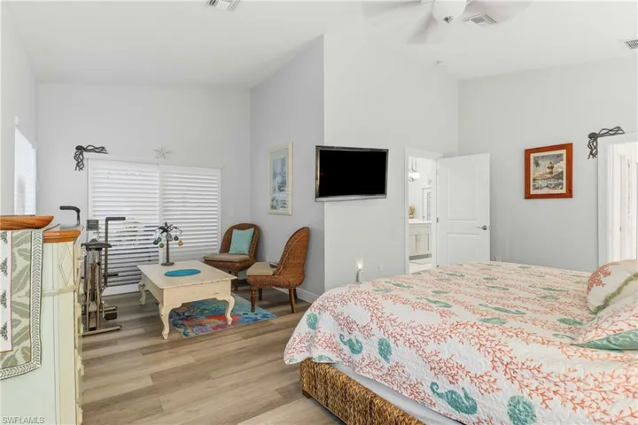 Bedroom with light wood-style floors, a ceiling fan, and high vaulted ceiling
