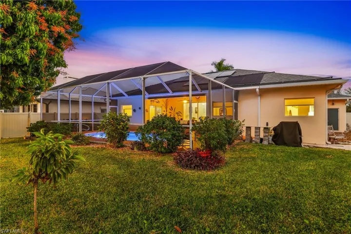 Rear view of house with a sunroom, stucco block, a lanai, and an outdoor pool solar heated.