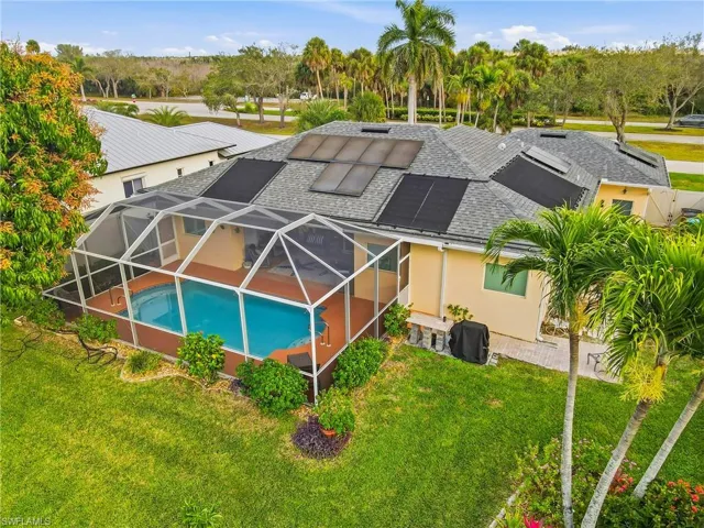 Back of house featuring an outdoor pool, a lanai, roof with shingles, stucco Block, and solar panels
