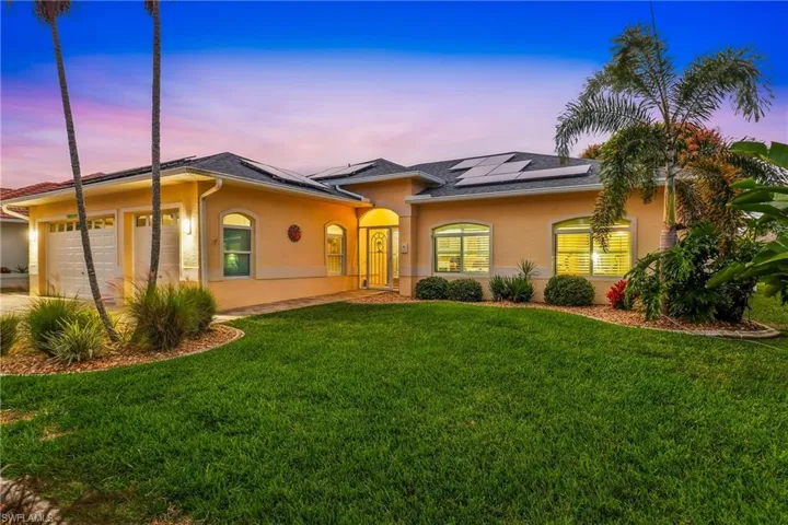 View of front of home featuring a front yard, a 3 car garage, stucco block, and solar panels