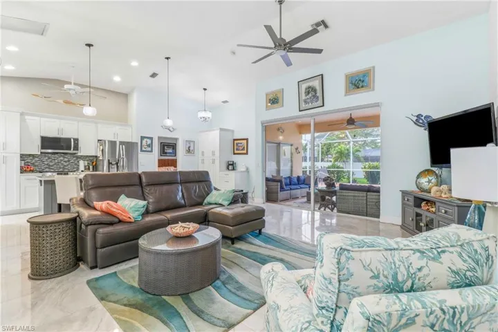 Living area with a ceiling fan, high vaulted ceiling, and light marble finish flooring