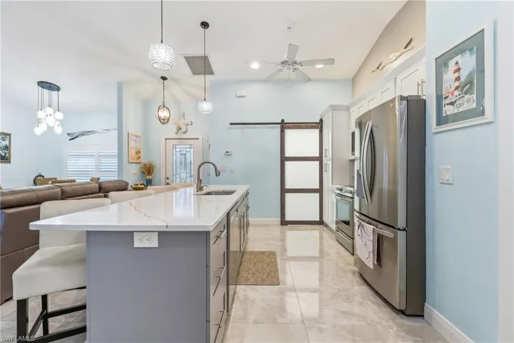 Kitchen with a ceiling fan, a barn door, white cabinetry, and stainless steel appliances