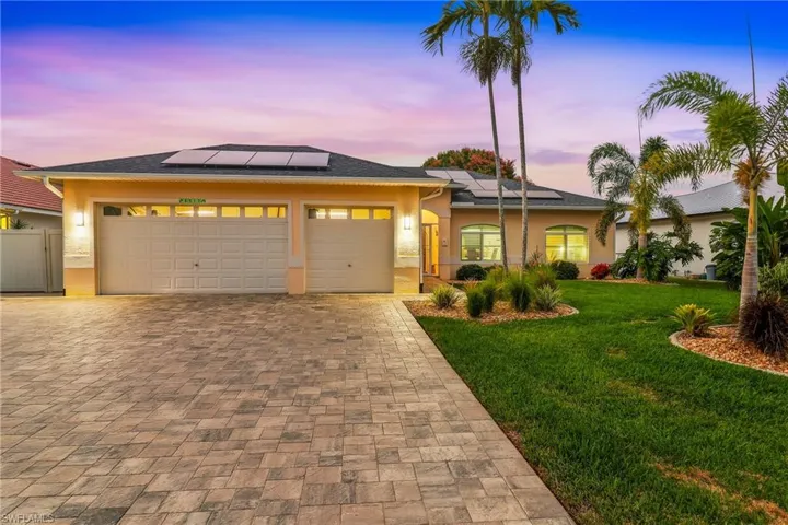 View of front facade featuring a yard, stucco block, decorative driveway, a 3 car garage, and solar panels