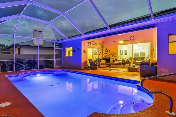 Outdoor pool featuring screen enclosure, a sunroom, a patio, and an outdoor living space