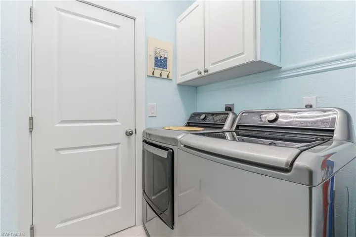 Laundry room with cabinet space, separate washer and dryer, and a textured wall