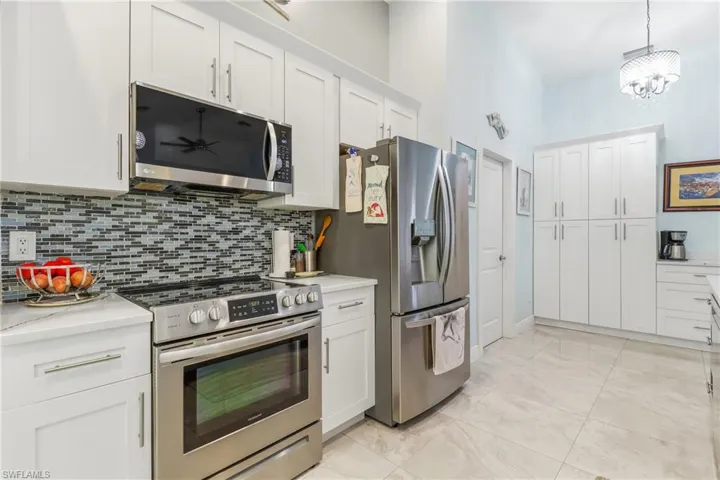 Kitchen with stainless steel appliances, white cabinets, and pendant lighting