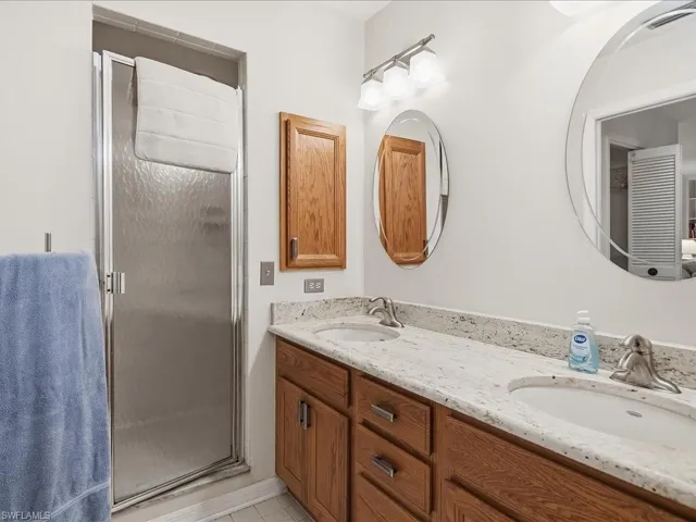 Primary bath with walk-in shower, vanity with double sinks, granite top, medicine cabinet and decor mirror and lights.