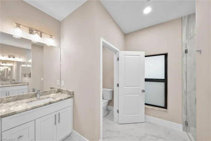 Bathroom featuring toilet, vanity, and walk in shower