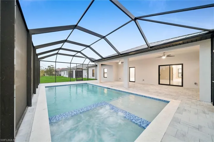 View of swimming pool featuring glass enclosure, ceiling fan, and a patio area