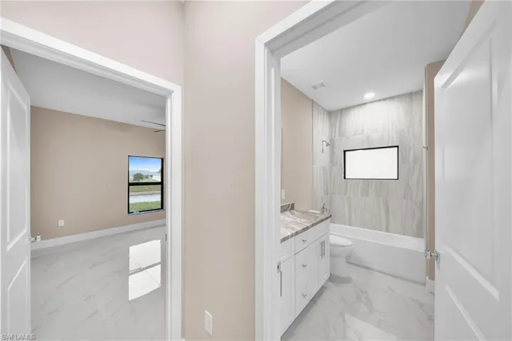 Full bathroom featuring vanity, tiled shower / bath combo, and toilet