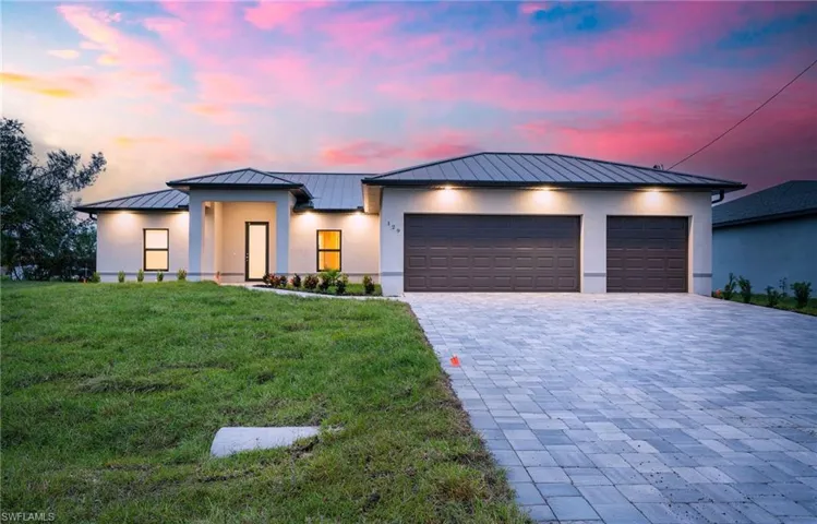 View of front of property featuring a lawn and a garage