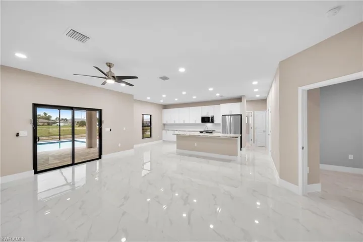 Kitchen featuring white cabinets, ceiling fan, a kitchen island with sink, and stainless steel appliances