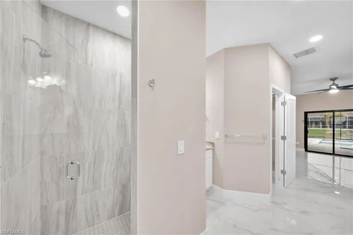 Bathroom featuring walk in shower, ceiling fan, and vanity