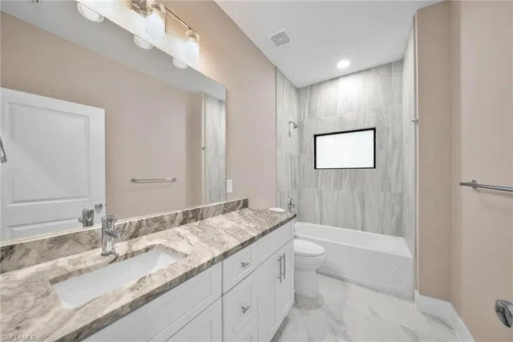 Full bathroom with vanity, tiled shower / bath, and toilet