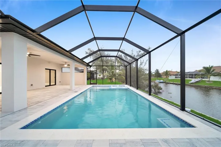 View of pool with a patio area, a water view, a lanai, and ceiling fan