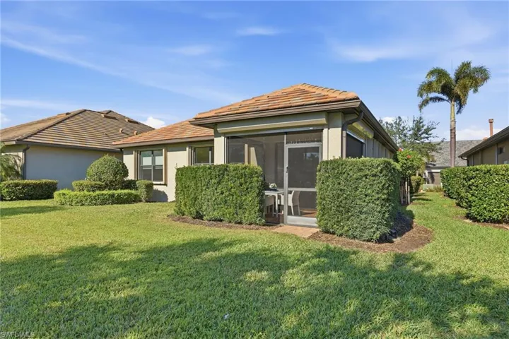 Rear view of house with a yard, stucco siding, a sunroom, and a tile roof