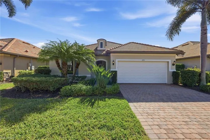 View of front facade with stucco siding, decorative driveway, an attached garage, a tiled roof, and a front lawn