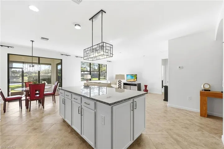 Kitchen featuring a chandelier, dark stone counters, decorative light fixtures, a center island, and recessed lighting