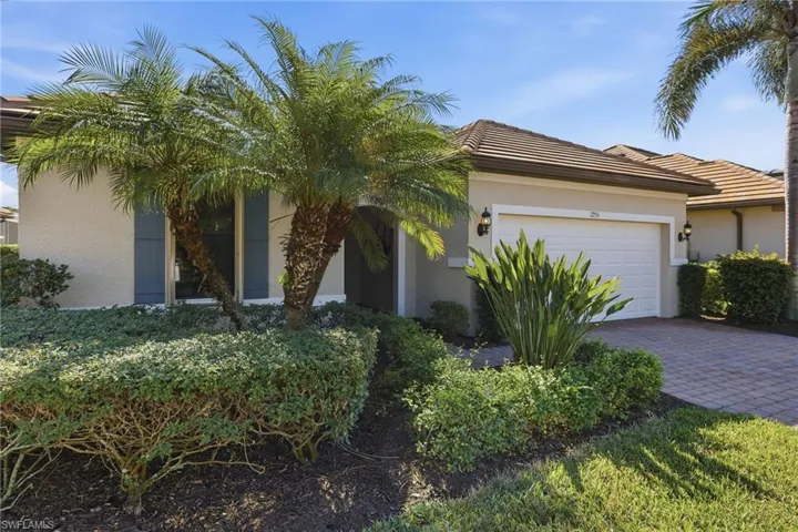 View of front of property with stucco siding, a tile roof, an attached garage, and decorative driveway
