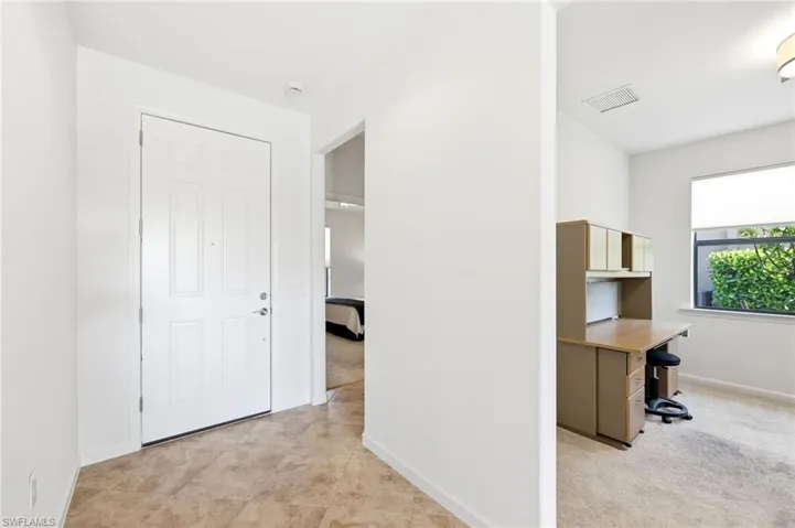 Hall featuring a desk and light carpet