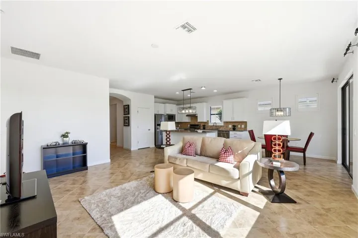 Living area with arched walkways, light tile patterned flooring, and recessed lighting