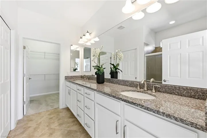 Bathroom featuring double vanity, a stall shower, and a walk in closet