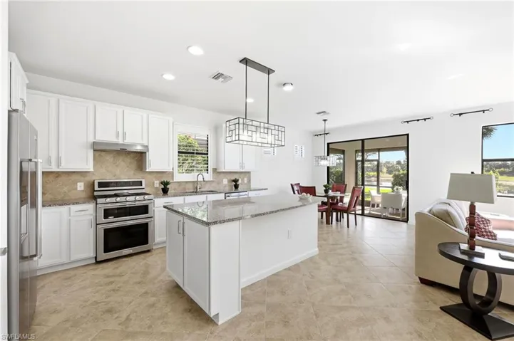 Kitchen with a kitchen island, appliances with stainless steel finishes, decorative light fixtures, white cabinetry, and recessed lighting