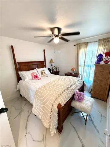 Bedroom with marble look tile flooring and a ceiling fan