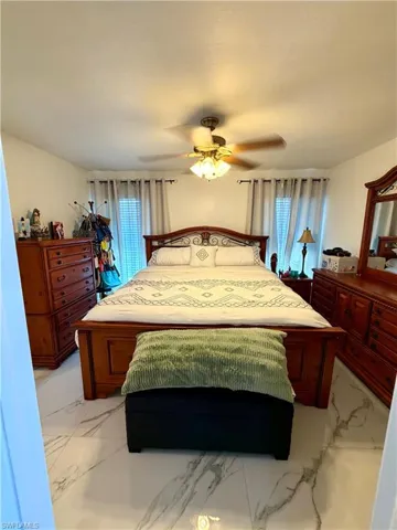 Bedroom with a ceiling fan and light marble finish flooring