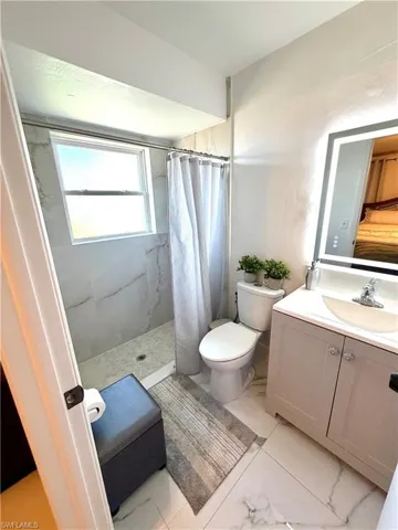 Full bathroom featuring vanity, a shower stall, and light marble finish floors