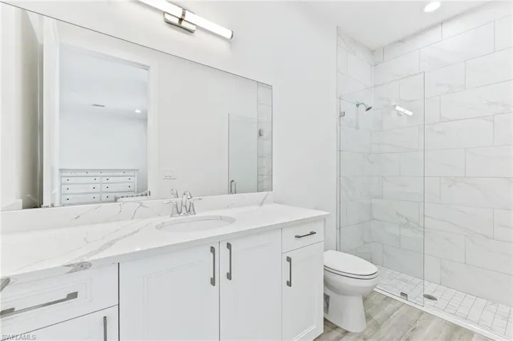 Bathroom with a shower stall, vanity, recessed lighting, and light wood-style flooring