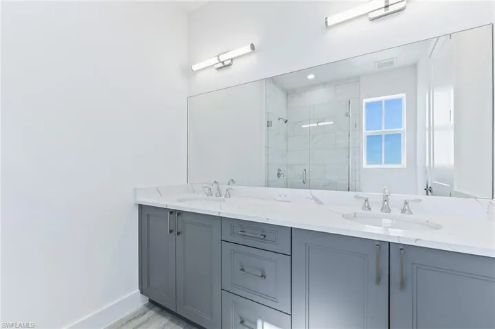 Full bathroom featuring double vanity and a marble finish shower