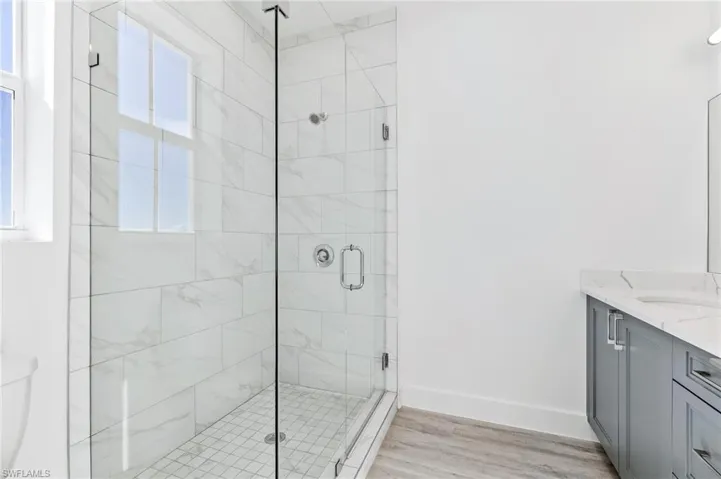 Full bathroom featuring a shower stall, vanity, and light wood-style flooring