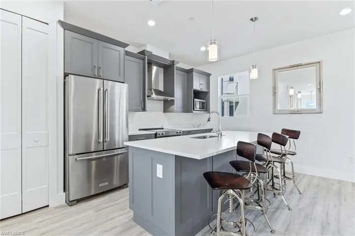 Kitchen with stainless steel appliances, gray cabinetry, pendant lighting, a kitchen breakfast bar, and recessed lighting