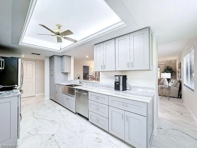 Kitchen with a tray ceiling, gray cabinetry, and light marble finish flooring