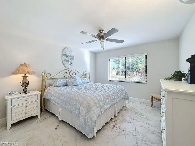 Bedroom featuring light marble finish floors and a ceiling fan